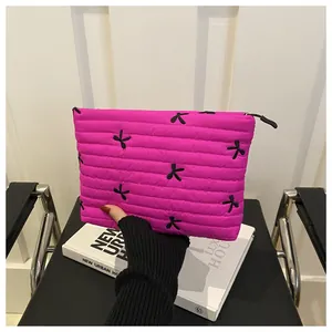 Detailed view of magenta quilted cosmetic bag with black bow embroidery and zipper