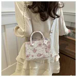 Détail du mini sac cabas à imprimé papillon rose porté par un mannequin
