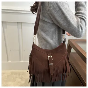 Detalle de bolso de hombro en ante marrón con flecos densos y hebilla metálica