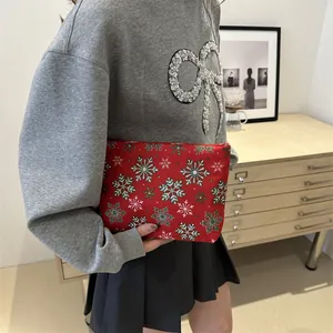 Red Christmas cosmetic bag with green and white snowflake patterns held by a model