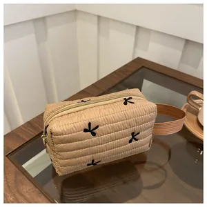 Detailaufnahme der gesteppten khakifarbenen Tasche mit schwarzen Schleifen und Reißverschluss