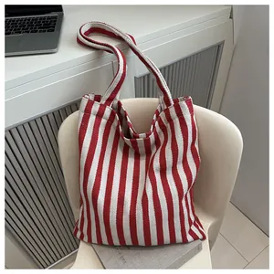 Macro detail of red and white striped canvas tote bag hanging on a white chair