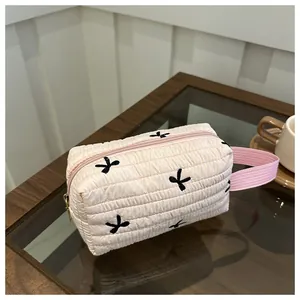 Detailaufnahme einer gesteppten rosa Kosmetiktasche mit schwarzen Schleifen