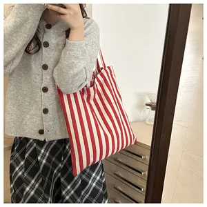 Detail of red and white striped canvas tote bag paired with grey cardigan and pleated skirt