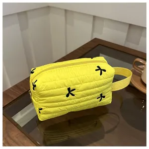 Detail der gelben gesteppten Kosmetiktasche mit schwarzen Schleifen und Reißverschluss