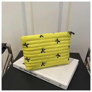 Macro detail of yellow quilted makeup bag with black bow embroidery and zipper texture