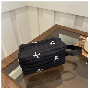 Detail der schwarzen gesteppten Tasche mit rosa Schleifenstickerei und Handgelenkschlaufe