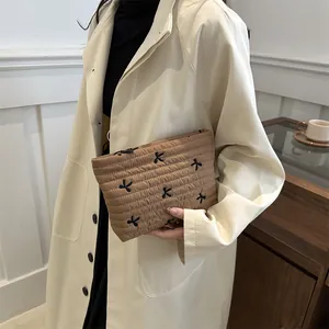 Quilted bow makeup bag in khaki brown held by a model in a minimalist stylish setting