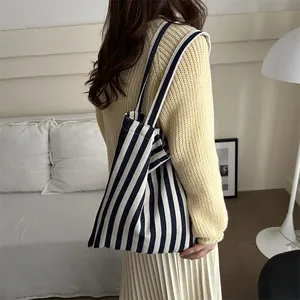 Minimalist navy blue and white striped canvas tote bag worn by a model in a bedroom