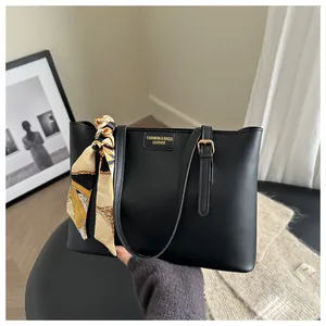 Detail of black leather tote bag with a decorative floral silk scarf on the handle
