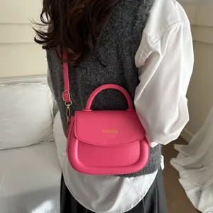 Roze PU-lederen schoudertas met handvat gedragen door een model in een wit shirt