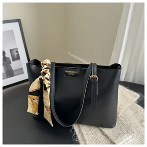 Detail of black leather tote bag with silk scarf handle and gold buckle adjustment