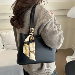 Classic black leather tote bag with decorative silk scarf handle on model in indoor setting
