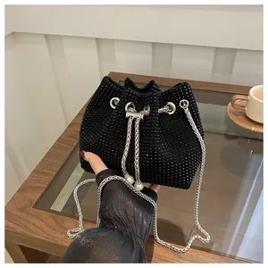 Detailed close-up of a black rhinestone bucket bag with silver chain and pearl accents