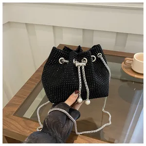 Detail of black rhinestone bucket bag with silver chain strap and pearl drawstring closure
