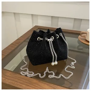 Macro detail of black rhinestone bucket bag with pearl drawstring and silver chain strap