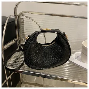 Détail de sac croissant noir tressé avec des ferrures dorées et fermeture éclair