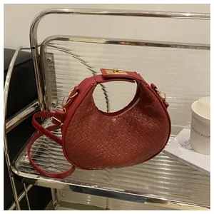 Détails du cuir tressé et du fermoir doré sur le sac demi-lune de couleur bordeaux