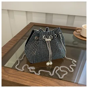 Close-up of sparkling rhinestones and pearl drawstring detail on black bucket bag