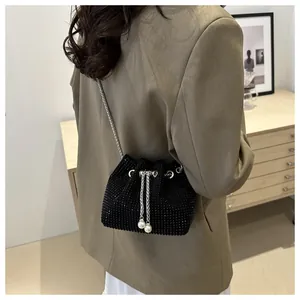 Detail of black rhinestone bucket bag featuring drawstring closure and pearl accents