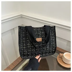 Gros plan du sac cabas en tweed noir et doré avec étiquette en cuir JINGPIN sur table