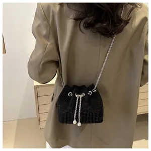 Detail of black rhinestone bucket bag with silver chain strap and pearl drawstring