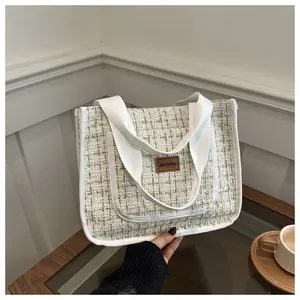 Gros plan du sac cabas en tweed avec écusson en cuir et poignées en tissu
