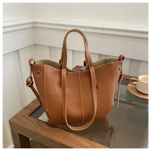 Detail showing high-quality brown pebbled leather texture with white contrast stitching on tote bag