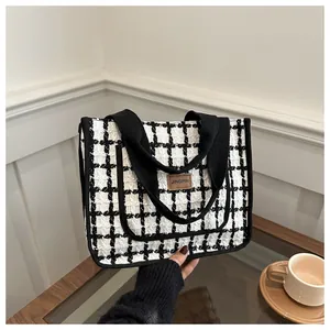 Détail du sac cabas en tweed à carreaux noir et blanc avec écusson logo en cuir