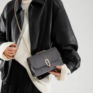 Dark grey minimalist square crossbody bag with gold oval lock and metal chain strap