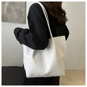 Dettaglio della trama della borsa tote intrecciata bianca indossata da una modella