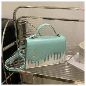 Detail of mint green piano-themed crossbody bag with gold clef embroidery on glass shelf