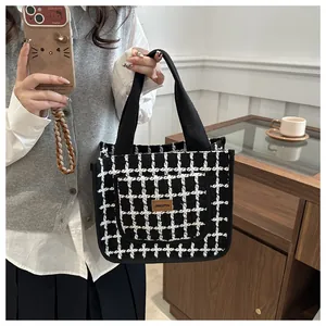 Détail du sac cabas à carreaux avec poignées tissées et étiquette en cuir sur la poche