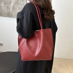 Grande borsa tote in pelle intrecciata rossa dallo stile minimalista indossata