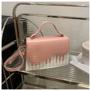 Detail of pink and white piano key crossbody bag featuring golden treble clef embroidery