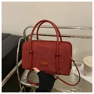 Detail of burgundy corduroy tote bag showing fine ribbed texture and stylish brand label