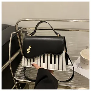Detail of piano key pattern handbag featuring a gold musical note hardware clasp