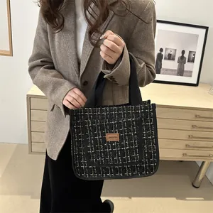 Sac à main cabas en tweed noir et doré avec poignées robustes et écusson décoratif chic