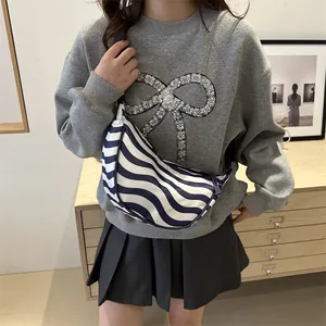 Sac croissant en toile à rayures bleues et blanches porté par un mannequin pour le quotidien