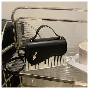 Detail of the piano key pattern and gold clef hardware on the black and white handbag