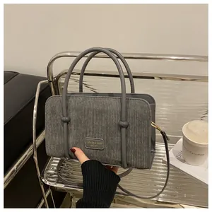 Detail of grey corduroy handbag featuring textured fabric and gold metal hardware
