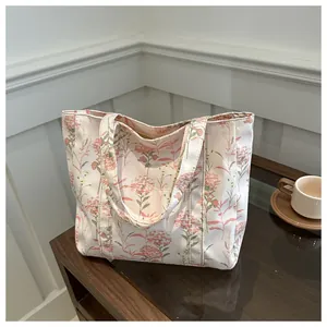 Close-up of floral canvas tote bag with pink flower patterns on a wooden surface