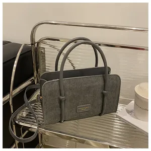 Detail of grey corduroy handbag with striped texture and knot-decorated round handles