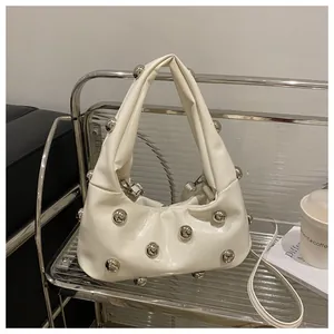 Macro view of white pleated PU handbag with silver metal ball studs on a chrome cart
