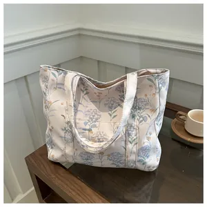 Detail view of floral canvas tote bag with blue hydrangeas on a wooden table