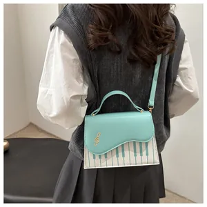 Detail of creative piano key crossbody bag featuring golden musical note emblem