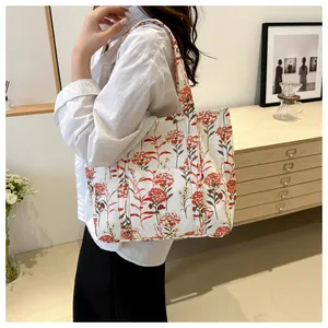 Detail of canvas tote bag featuring vibrant red floral prints and handy front pocket