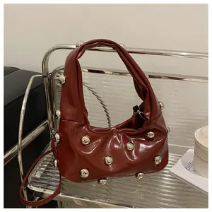 Detail of red-brown patent leather handbag with silver studs on a stylish chair
