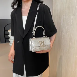 Silver crocodile pattern handbag with gold logo shown on model for a trendy look