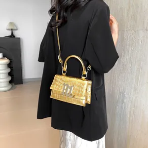 Golden crocodile pattern handbag with metal M buckle shown on model in black suit